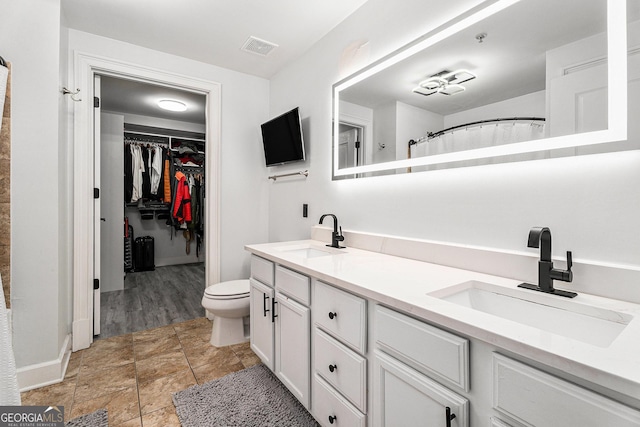 bathroom featuring double vanity, toilet, visible vents, and a sink