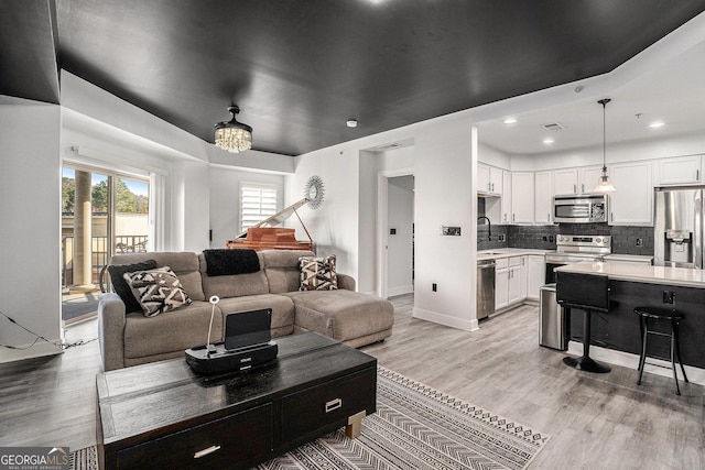 living area with visible vents, baseboards, light wood-style flooring, recessed lighting, and a notable chandelier