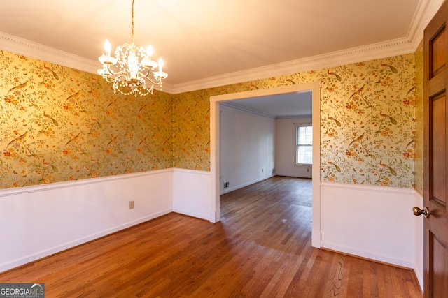 spare room featuring wallpapered walls, crown molding, wood finished floors, and a wainscoted wall