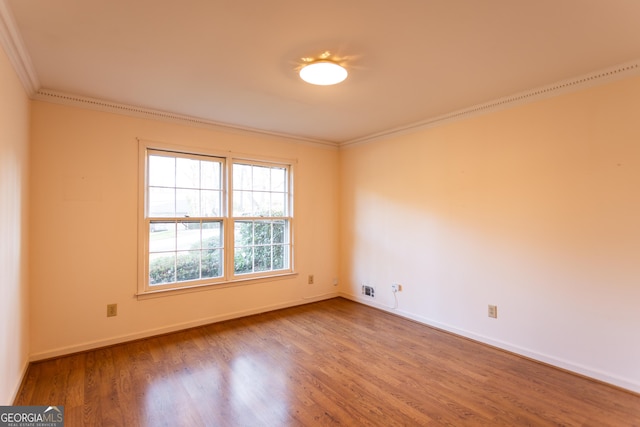 spare room featuring crown molding, wood finished floors, and baseboards