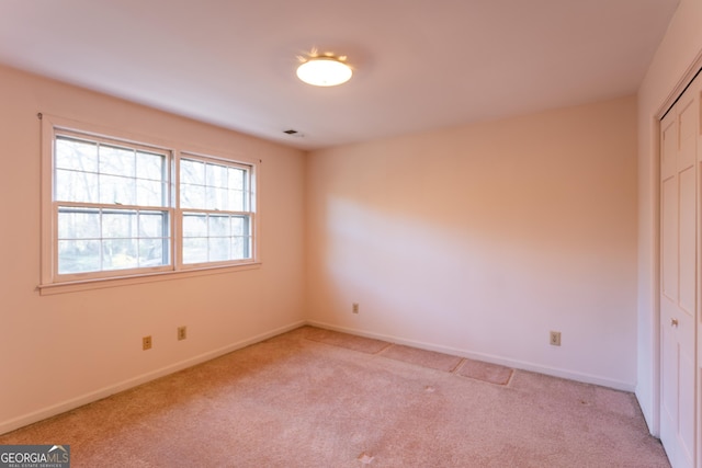 unfurnished bedroom with light carpet, visible vents, baseboards, and a closet