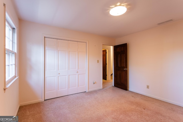 unfurnished bedroom with a closet, visible vents, baseboards, and carpet