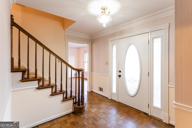 foyer entrance featuring baseboards, a notable chandelier, ornamental molding, and stairs