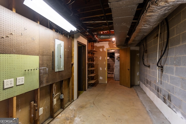 unfinished basement featuring electric panel and concrete block wall