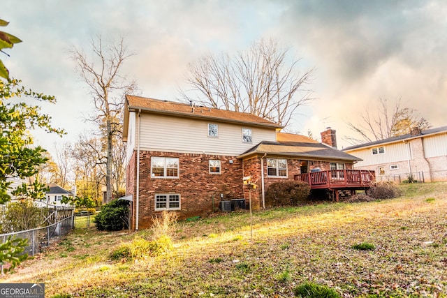 back of house featuring a chimney, a fenced backyard, brick siding, and a wooden deck