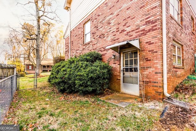 property entrance with fence, brick siding, and a gate