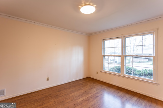 empty room with crown molding, baseboards, and wood finished floors