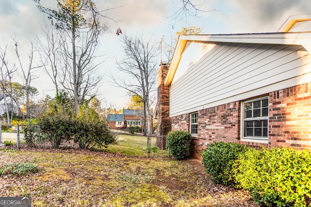 exterior space with brick siding, a chimney, and fence