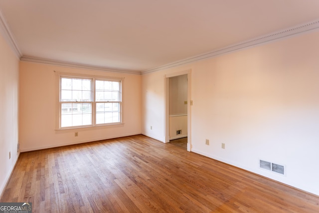 empty room featuring visible vents, baseboards, wood finished floors, and crown molding