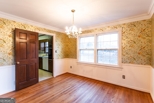 unfurnished dining area featuring wallpapered walls, light wood-style flooring, and a wainscoted wall