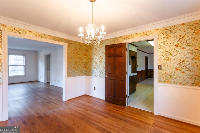 empty room featuring wallpapered walls, wood finished floors, and wainscoting