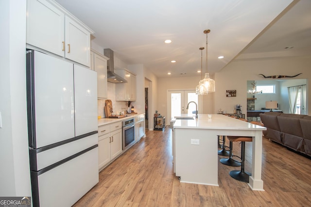 kitchen featuring open floor plan, a breakfast bar area, appliances with stainless steel finishes, light wood-style floors, and a sink