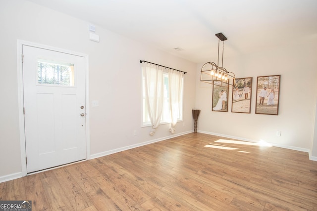 foyer with a notable chandelier, light wood-style flooring, and baseboards