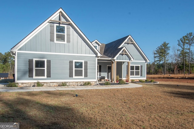 view of front of home featuring a porch, board and batten siding, a front yard, and roof with shingles