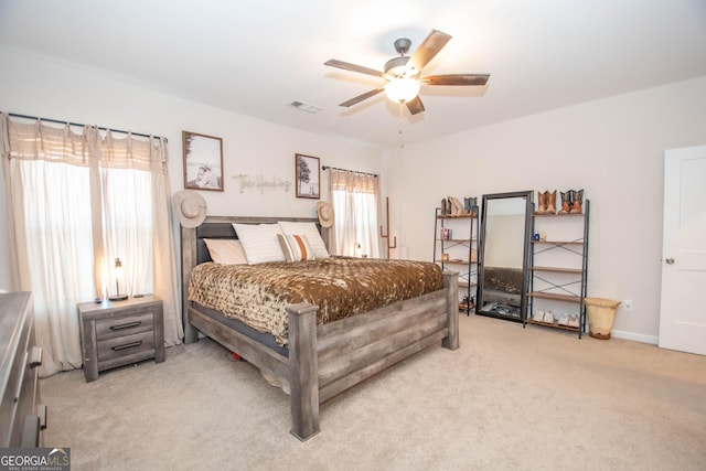 bedroom with visible vents, light colored carpet, and ceiling fan