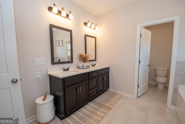 bathroom with a sink, baseboards, toilet, and double vanity