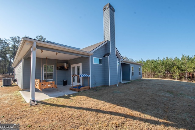 back of property featuring a yard, a chimney, french doors, central air condition unit, and a patio area