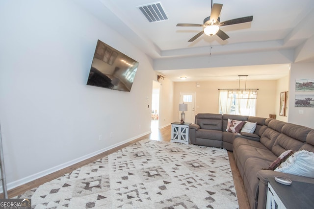 living room featuring visible vents, a raised ceiling, and baseboards