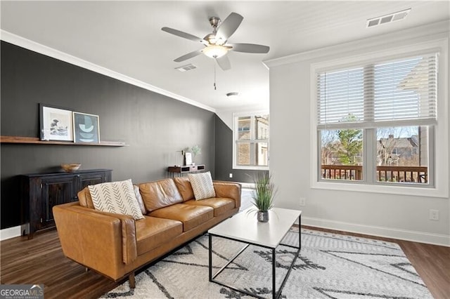 living room featuring visible vents, baseboards, wood finished floors, and crown molding