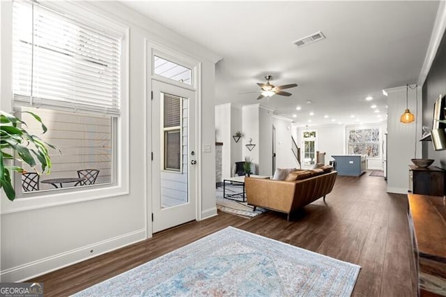 living room with ceiling fan, visible vents, baseboards, and dark wood-style floors