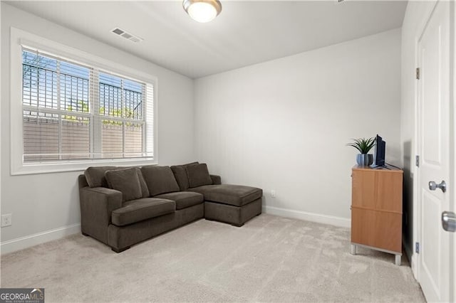 living area featuring visible vents, baseboards, and light colored carpet