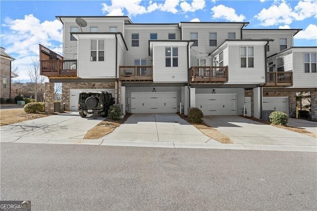 multi unit property featuring central air condition unit, concrete driveway, and a garage