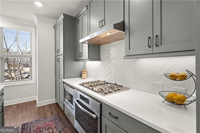 kitchen featuring under cabinet range hood, decorative backsplash, gray cabinetry, and stainless steel appliances