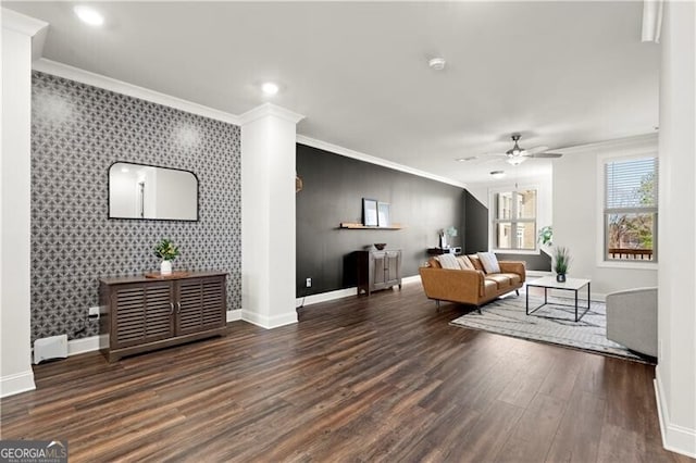 living area featuring an accent wall, crown molding, wood finished floors, and baseboards