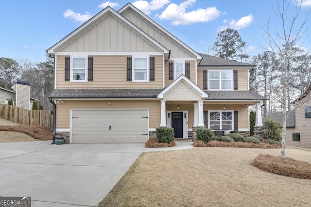 craftsman inspired home featuring stone siding, fence, board and batten siding, concrete driveway, and a garage