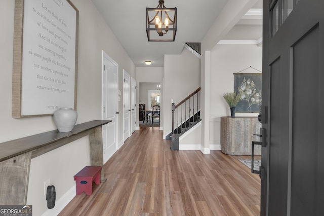 entryway with a chandelier, stairway, baseboards, and wood finished floors