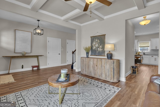 living room featuring beam ceiling, wood finished floors, coffered ceiling, and ceiling fan