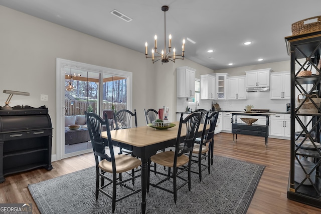 dining area featuring a chandelier, visible vents, recessed lighting, and wood finished floors