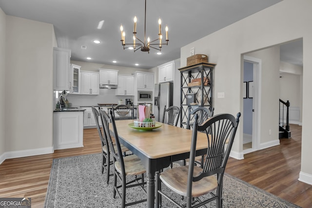 dining room featuring a notable chandelier, wood finished floors, recessed lighting, and baseboards