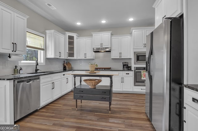 kitchen featuring under cabinet range hood, appliances with stainless steel finishes, white cabinetry, and wood finished floors