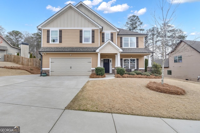 craftsman-style house featuring board and batten siding, fence, driveway, stone siding, and an attached garage