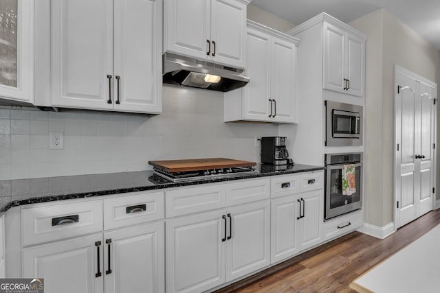 kitchen with backsplash, under cabinet range hood, stainless steel appliances, wood finished floors, and white cabinetry