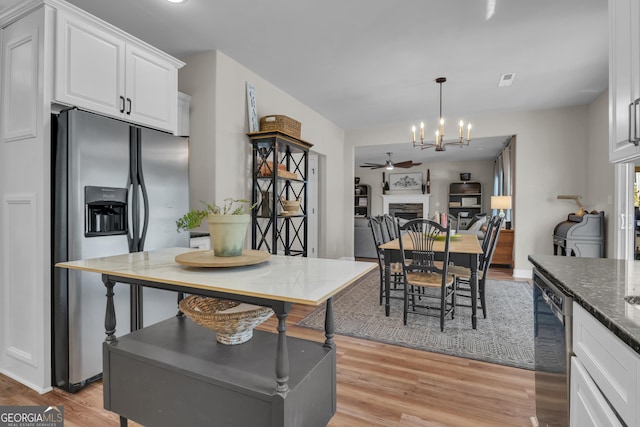 kitchen featuring light wood-style flooring, dark stone countertops, white cabinetry, stainless steel appliances, and a fireplace