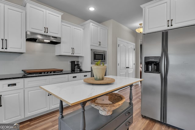 kitchen with white cabinetry, decorative backsplash, under cabinet range hood, and stainless steel appliances