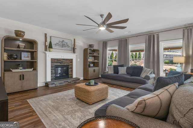 living area with dark wood-style floors, ceiling fan, and a fireplace