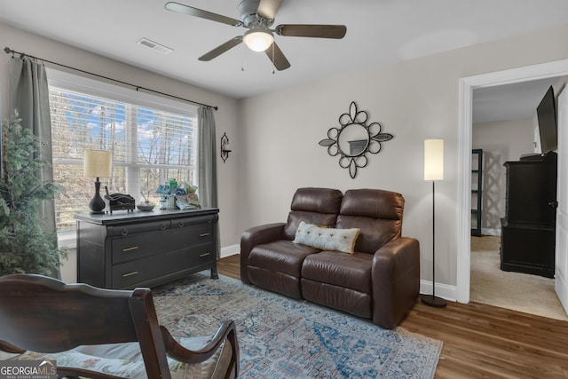 living room with visible vents, baseboards, ceiling fan, and wood finished floors