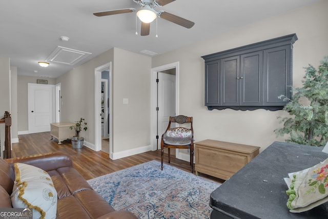 living room with baseboards, attic access, wood finished floors, and a ceiling fan