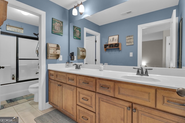 bathroom with tile patterned floors, double vanity, toilet, and a sink