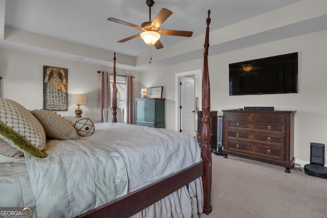 carpeted bedroom featuring a ceiling fan and a tray ceiling