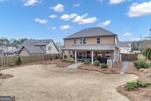 rear view of house with a patio, a shingled roof, and a fenced backyard