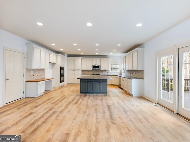 kitchen with a wealth of natural light, appliances with stainless steel finishes, white cabinetry, and light wood-type flooring