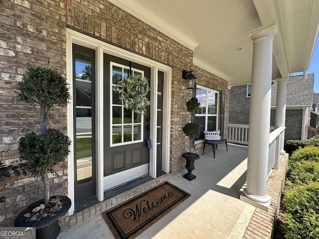 entrance to property featuring covered porch and brick siding