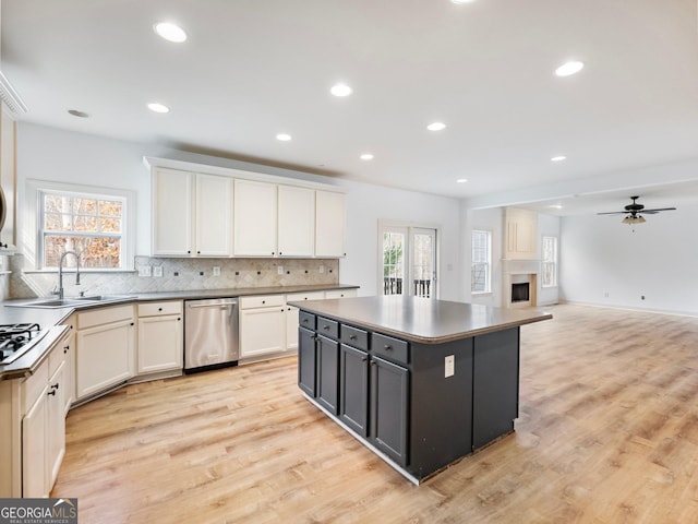 kitchen with tasteful backsplash, a kitchen island, dishwasher, light wood-type flooring, and a fireplace