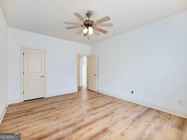 spare room with baseboards, light wood-style floors, and a ceiling fan