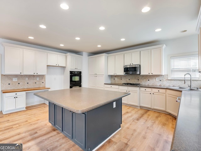 kitchen featuring tasteful backsplash, appliances with stainless steel finishes, a sink, and white cabinets