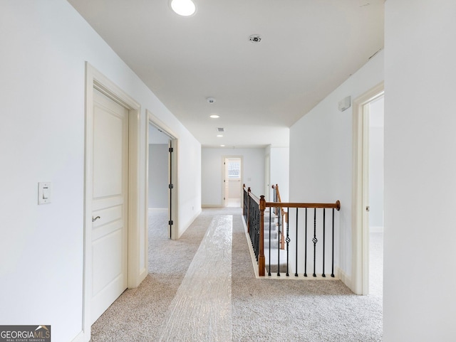 hall featuring an upstairs landing, light colored carpet, recessed lighting, and baseboards